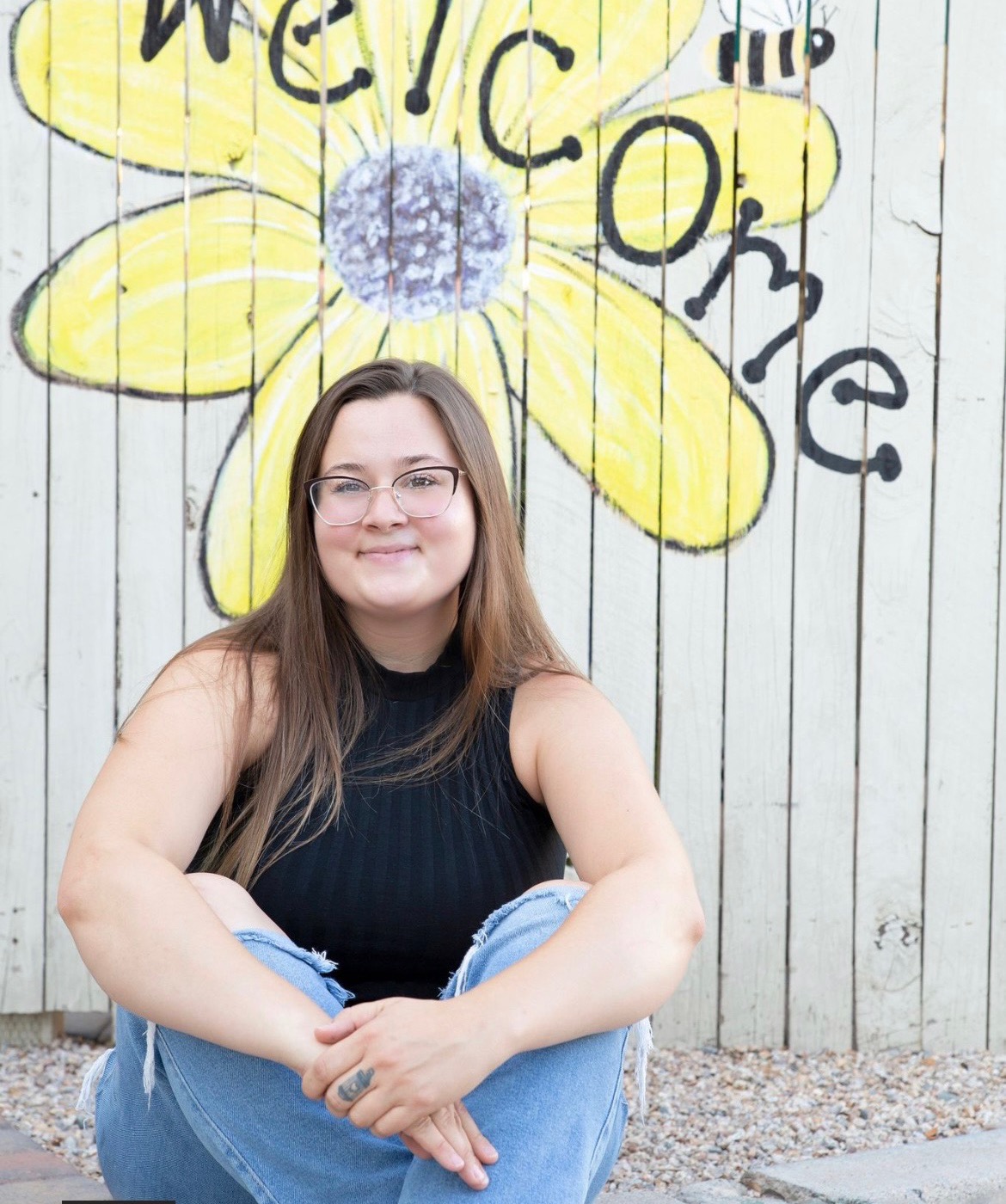 Soraya smiling in front of a Welcome mural